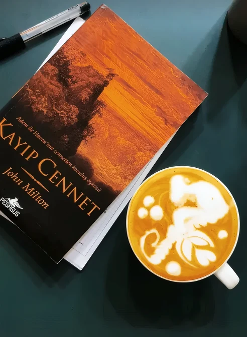 Latte art yapılmış kahve ve Kayıp Cennet kitabı